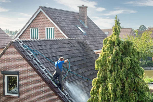 Cleaner with pressure washer at roof house cleaning roof tiles — Stock Photo, Image