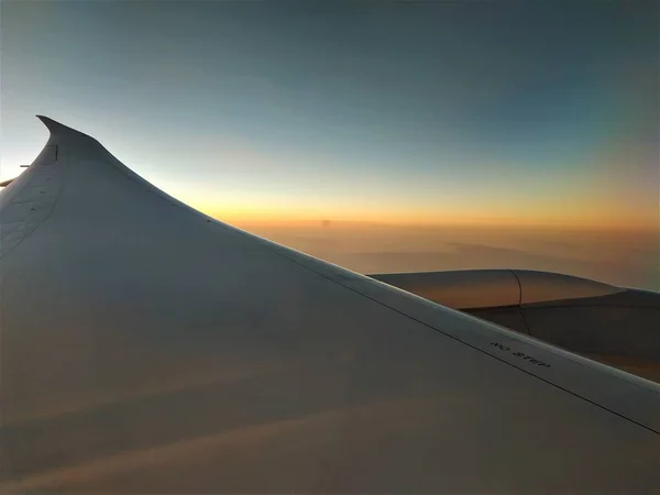 View out of plane window over wing into sunset — Stock Photo, Image
