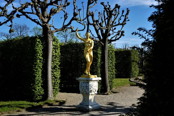 Herrenhausen Bahçeleri 'ndeki ağaçların ve çalıların önündeki altın Venüs.
