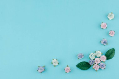 Mavi tonu kağıt çiçekler ve kopya alanı pastel mavi zemin üzerine yeşil yaprakları