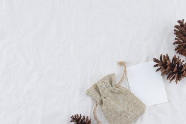Boş beyaz kartı, çul çanta ve pinecones kopya alanı muslin kumaş zemin üzerine
