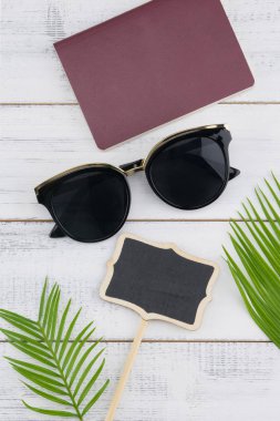 Güneş gözlüğü, küçük Pano ve pasaport eğreltiotu yaprakları üzerinde beyaz tahta arka plan ile