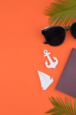 Güneş gözlüğü ve pasaport eğreltiotu yaprakları ve küçük Yelkenli ve kopya alanı turuncu zemin üzerine çapa ile süsleyin