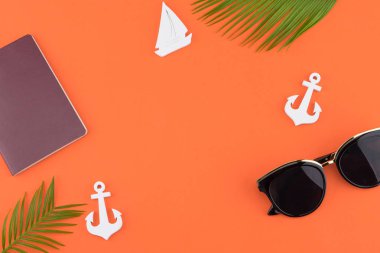 Güneş gözlüğü ve pasaport eğreltiotu yaprakları ve küçük Yelkenli ve kopya alanı turuncu zemin üzerine çapa ile süsleyin