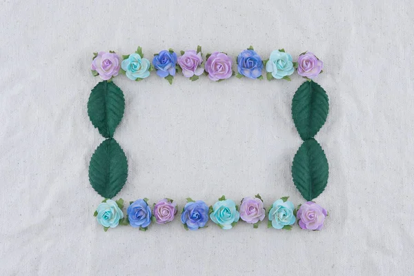 Square wreath made from blue tone rose paper flowers and green leaves on muslin fabric with copy space