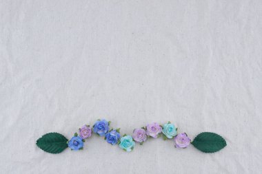 Mavi tonu gül kağıt çiçekler ve yeşil yaprakları ile kopya alanı muslin kumaş üzerine yapılan çelenk