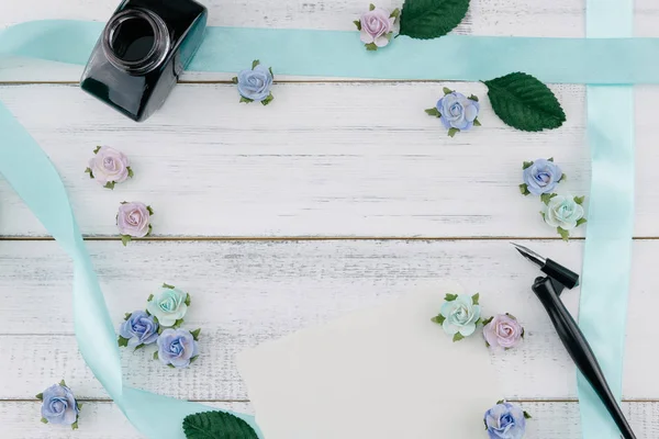 空白の白いカード 斜めのペンとインクのボトルと青色のトーン紙の花を飾るし コピー スペースを持つ木材白地リボン — ストック写真