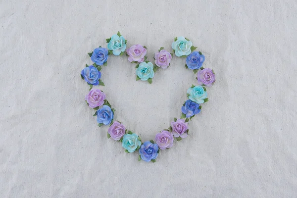 Heart shape wreath made from blue tone rose paper flowers on muslin fabric with copy space