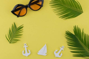 Eğreltiotu yaprakları ve küçük Yelkenli ve kopya alanı sarı zemin üzerine çapa ile güneş gözlüğü süslemeleri