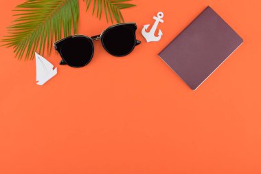Güneş gözlüğü ve pasaport eğreltiotu yaprakları ve küçük Yelkenli ve kopya alanı turuncu zemin üzerine çapa ile süsleyin