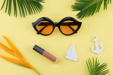 Güneş gözlüğü ve dudak parlatıcısı süslemeleri küçük Yelkenli, çapa, cennet kuşu çiçeği ve sarı zemin üzerine eğreltiotu yaprakları