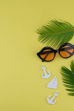 Eğreltiotu yaprakları ve küçük Yelkenli ve kopya alanı sarı zemin üzerine çapa ile güneş gözlüğü süslemeleri