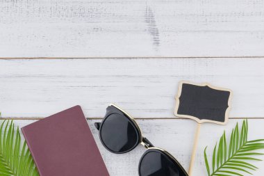 Güneş gözlüğü, küçük Pano ve pasaport eğreltiotu yaprakları üzerinde kopya alanı ile beyaz tahta arka plan ile