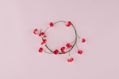 Şube kopya alanı ile pembe arka plan üzerinde kırmızı kağıt çiçeklerle yapılan yuvarlak çelenk
