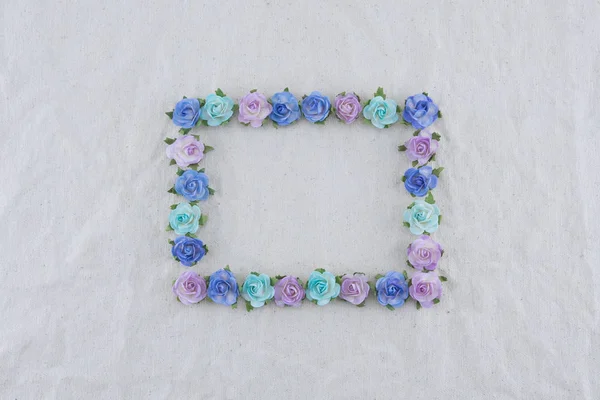 Square wreath made from blue tone rose paper flowers on muslin fabric with copy space