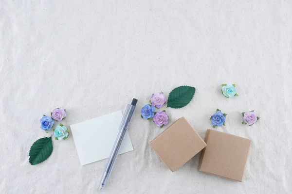 コピー スペースとモスリン生地に青のトーン紙の花と白い空白のカード ブラウン ギフト ボックスを飾る — ストック写真