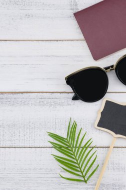 Güneş gözlüğü, küçük Pano ve pasaport kopyası sapce Beyaz ahşap zemin üzerine eğreltiotu yaprakları ile