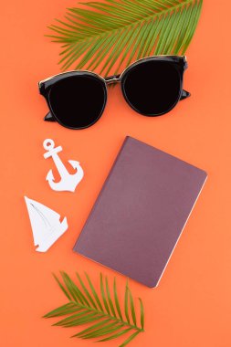 Güneş gözlüğü ve pasaport eğreltiotu yaprakları ve küçük Yelkenli ve turuncu zemin üzerine çapa ile süsleyin 