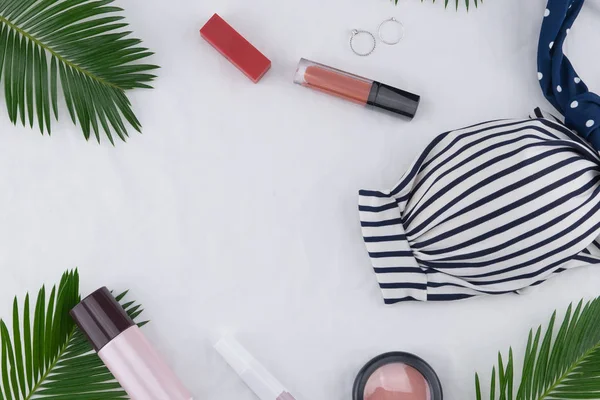 Bikini top, skin care and cosmetic decorate with fern leaves on white background with copy space, selective focus on bikini, skin care and cosmetic