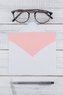 Beyaz boş pembe kart örtmek, gözlük ve beyaz tahta arka plan üzerinde siyah kalem