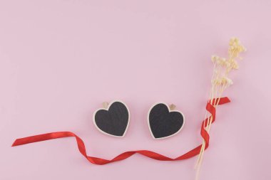 İki kalp şekli kurulu süslemeleri beyaz Kuru çiçekler Buket ve kopya alanı ile pastel pembe arka plan üzerinde kırmızı kurdele ile