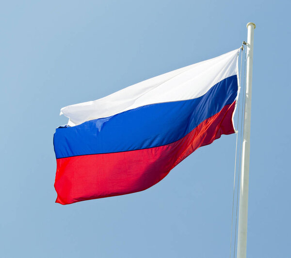 russian flag waving in the wind with blue sky as background.