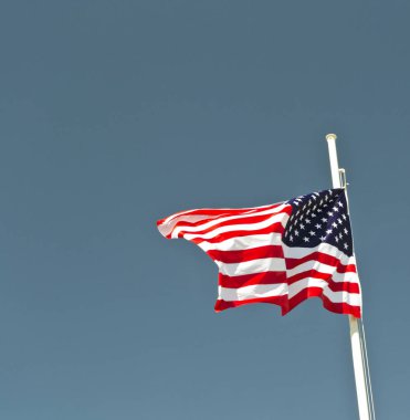 arka plan olarak mavi gökyüzü ile rüzgarda sallayarak ABD bayrağı.