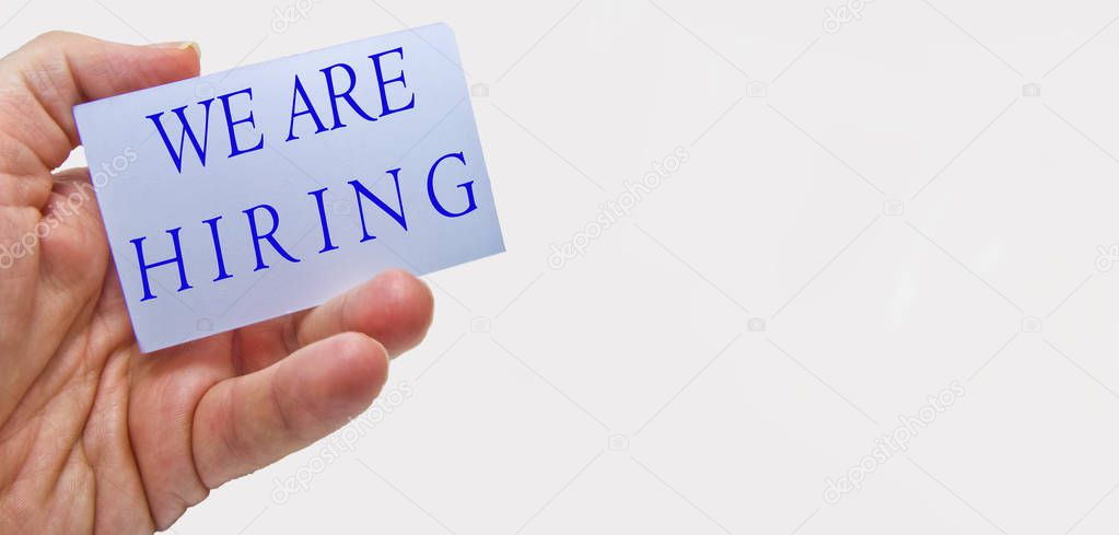 Job recruiting advertisement represented by 'WE ARE HIRING' texts on cards in man's hands
