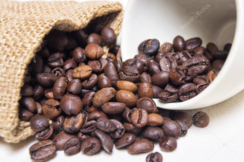 roasted coffee beans with raw textile and white porcelain coffee cup