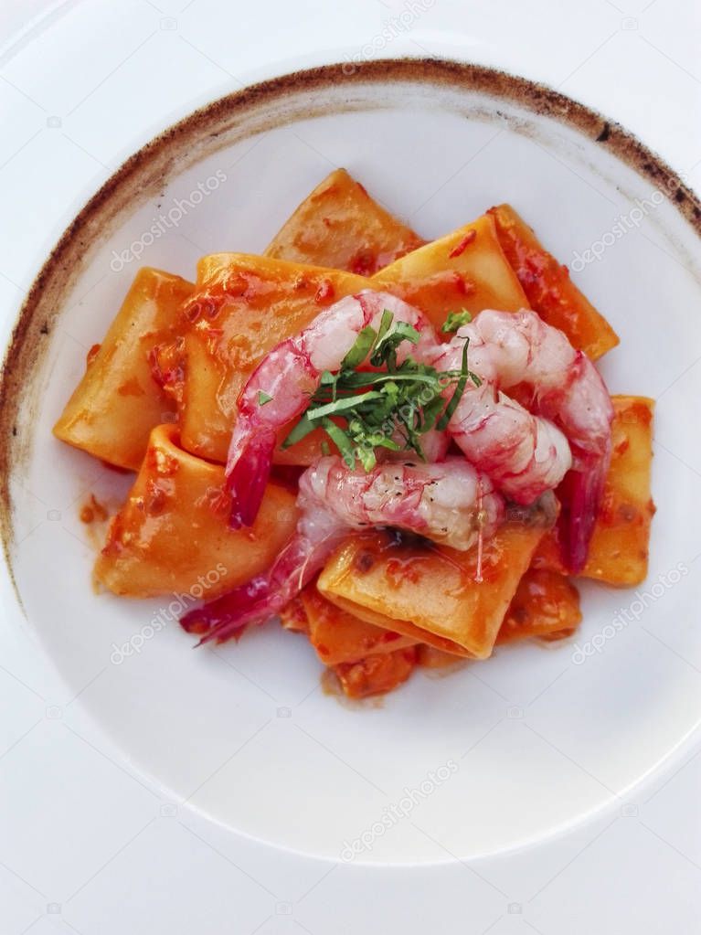 italian traditional paccheri (short pasta from gragnano) with shrimps and burned onions cream