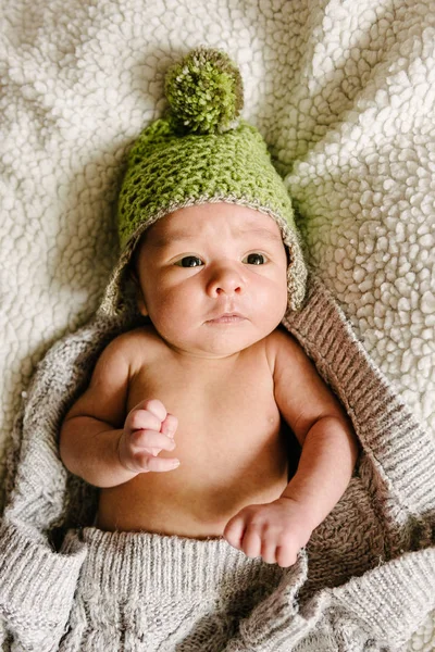 Un bebé recién nacido en un sombrero yace en una cuna . — Foto de Stock