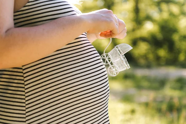 임신한 여자의 뱃속에 화이트 장난감 유모차 — 스톡 사진