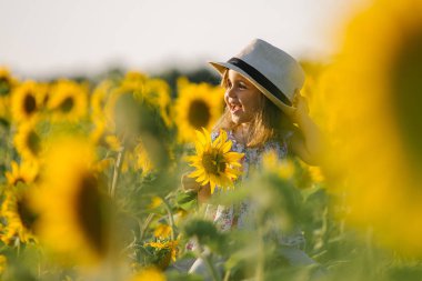 Çocuk ve ayçiçeği, yaz, Doğa ve eğlence. Yaz tatili. Küçük kız bir ayçiçeği koklama