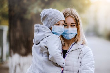 bir kız bir çocukla koruyucu tıbbi maske de yol anlamına gelir. Yoğun duman sokaklarda. Grip salgını
