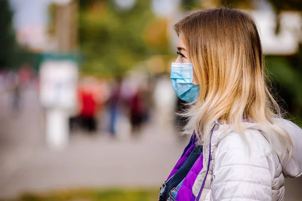 La fille est debout près de la route dans un masque médical de protection. smog dense dans les rues de la ville . — Photo