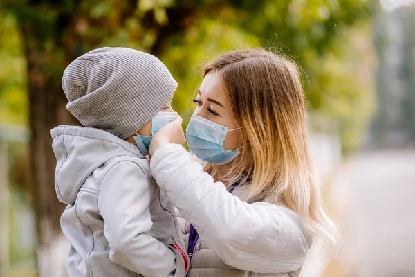 Une fille avec un enfant se tient sur la route dans un masque médical de protection. Du smog dense dans les rues. Épidémie de grippe — Photo