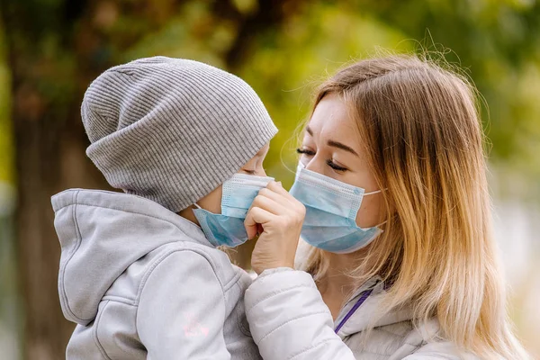 Uma menina com uma criança fica na estrada com uma máscara médica protetora. Névoa densa nas ruas. Epidemia da gripe — Fotografia de Stock