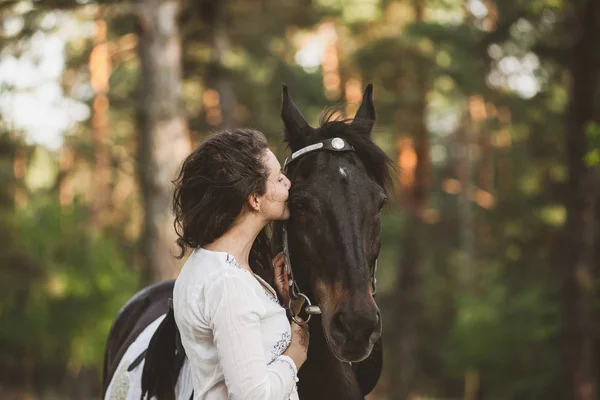 Sorrindo menina abraça seu animal de estimação cavalo — Fotografia de Stock