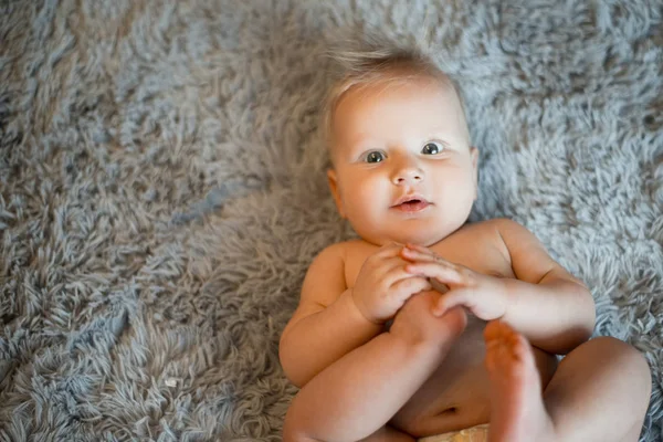 재미 있는 작은 아기 침대에 회색 솜 털 담요에 기저귀를 착용. 목욕 또는 샤워 후 아기입니다. 기저귀의 변화와 피부 관리. 그의 다리를가지고 노는 귀여운 아기 — 스톡 사진