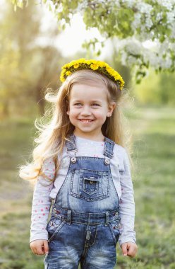 Kameraya bakarak karahindiba çelenk ile poz bir şirin 4 yaşındaki kızı bahar güneşli portresi