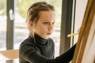 Genç kız bir branda ile şövale üzerinde çizim