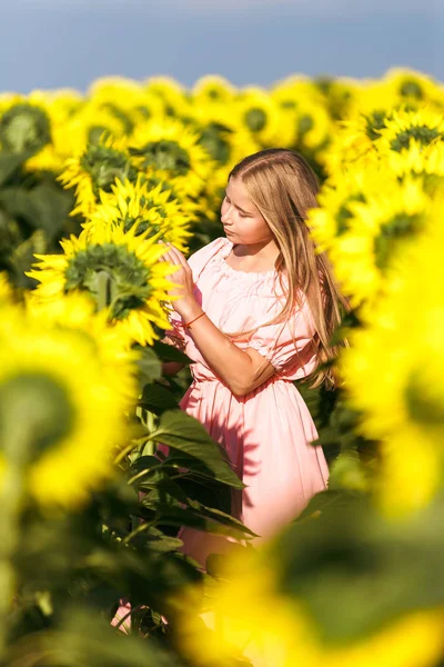 Mooie tiener meisje staande onder zonnebloemen, poseren voor camera met ogen gesloten — Stockfoto