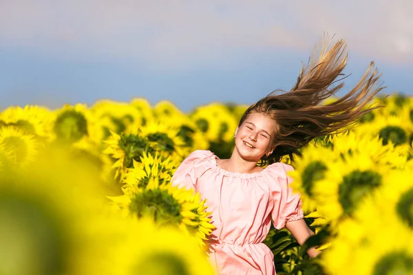 Vacker flicka studsade i ett fält av solrosor jubel liv — Stockfoto