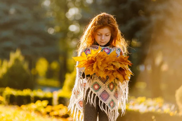 Hermosa chica cabeza roja sosteniendo hojas de otoño y posando para la cámara, foto colorida —  Fotos de Stock
