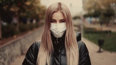 Kız koruyucu tıbbi maskeli karayoluyla duruyor. Şehrin sokaklarında yoğun duman.