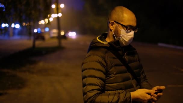 Un homme masqué la nuit près de la route parlant sur un téléphone portable. Virus et protection contre la pollution — Video