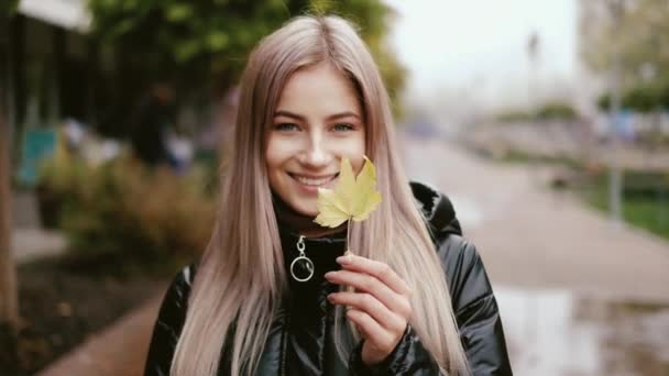 Портрет счастливой девушки с кленовым листом в руках — стоковое видео