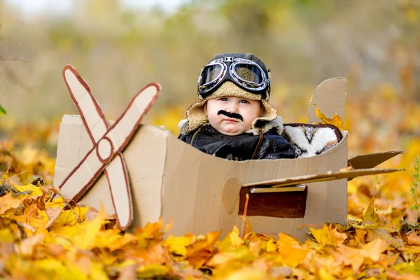 Ragazzo molto carino seduto in aereo di cartone, futuro pilota, professione sogno a vita — Foto Stock