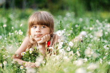 Güzel kız papatya tarlasında yatıyor ve kameraya gülümsüyor, doğayla bütünlük, çocukluk.