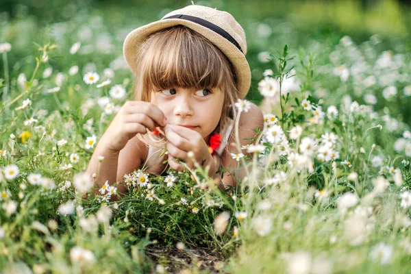Chica bonita acostada en el campo de margaritas y sonriendo a la cámara, la unidad con la naturaleza, la infancia — Foto de Stock